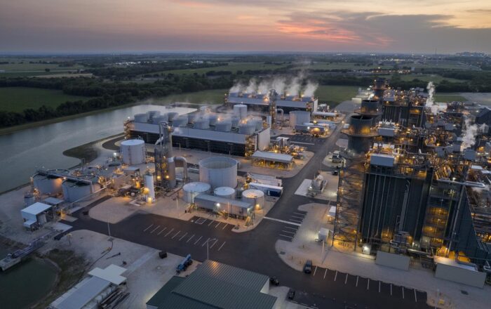 An aerial sunset photo of BKV's Temple 1 natural gas power plant at sunset, along the water with verdant greenery on the opposite bank