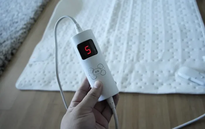 person holding an electric blanket remote