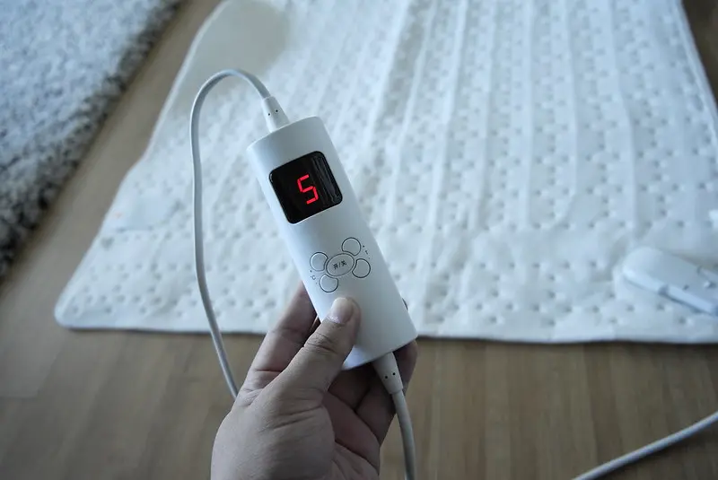 person holding an electric blanket remote